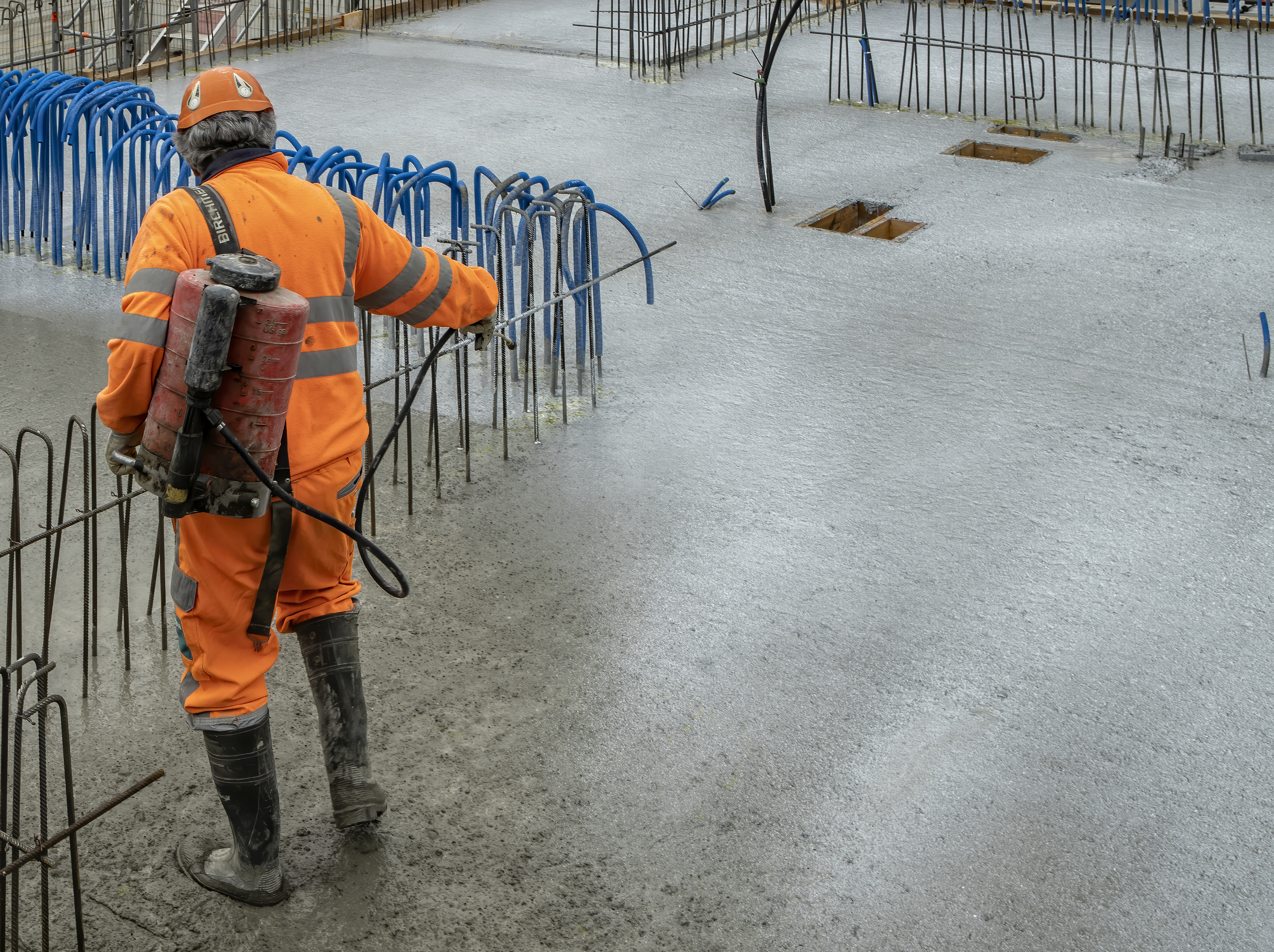 Man applying Sika® Antisol® curing compound on concrete on construction site with reinforcement